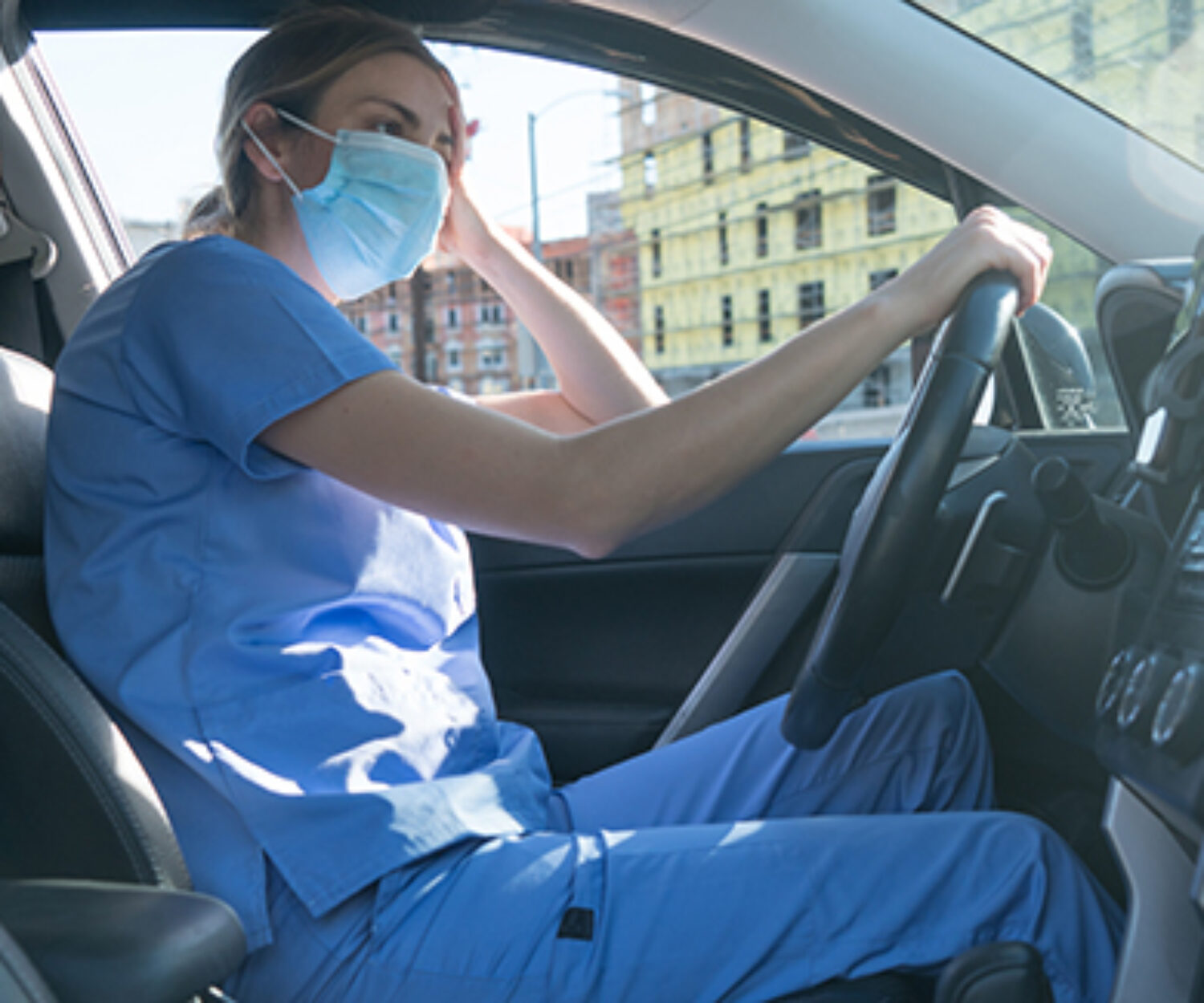 A nurse hangs her head in her car after seeing coronavirus patients.